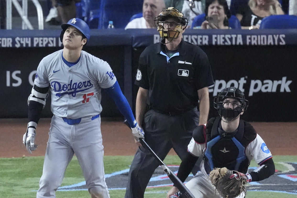 Los Angeles Dodgers' Shohei Ohtani, left, of Japan, watches the ball as he hits a home run, scoring Max Muncy and Chris Taylor, during the ninth inning of a baseball game against the Miami Marlins, Thursday, Sept. 19, 2024, in Miami. (AP Photo/Wilfredo Lee)