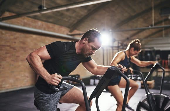 A man and a woman working out on elliptical machines.