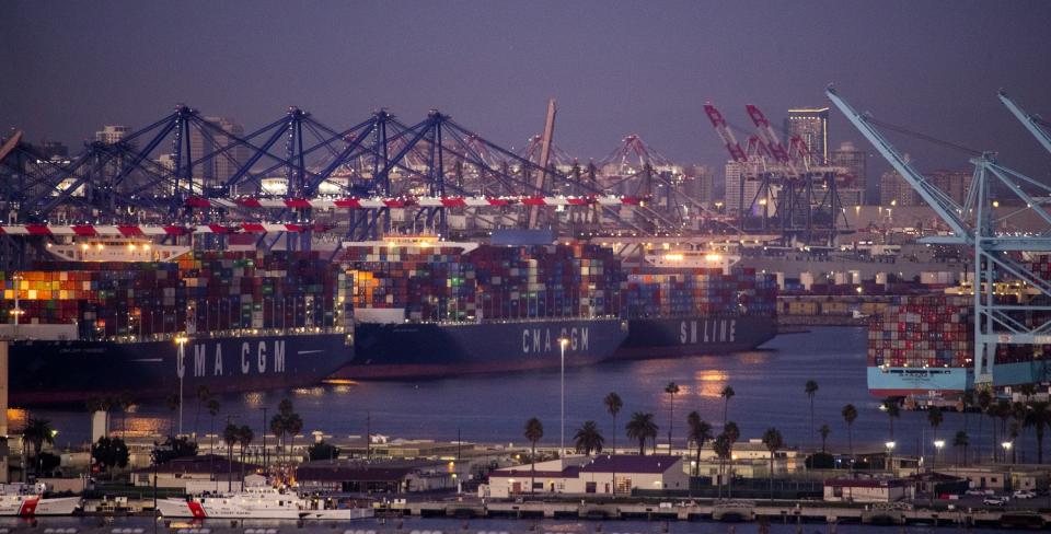 Numerous container ships are shown at sea.