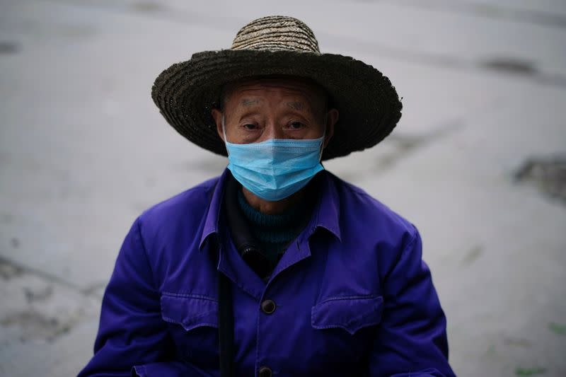 Street vendor wearing a face mask is seen as his vegetable stall in Jingzhou