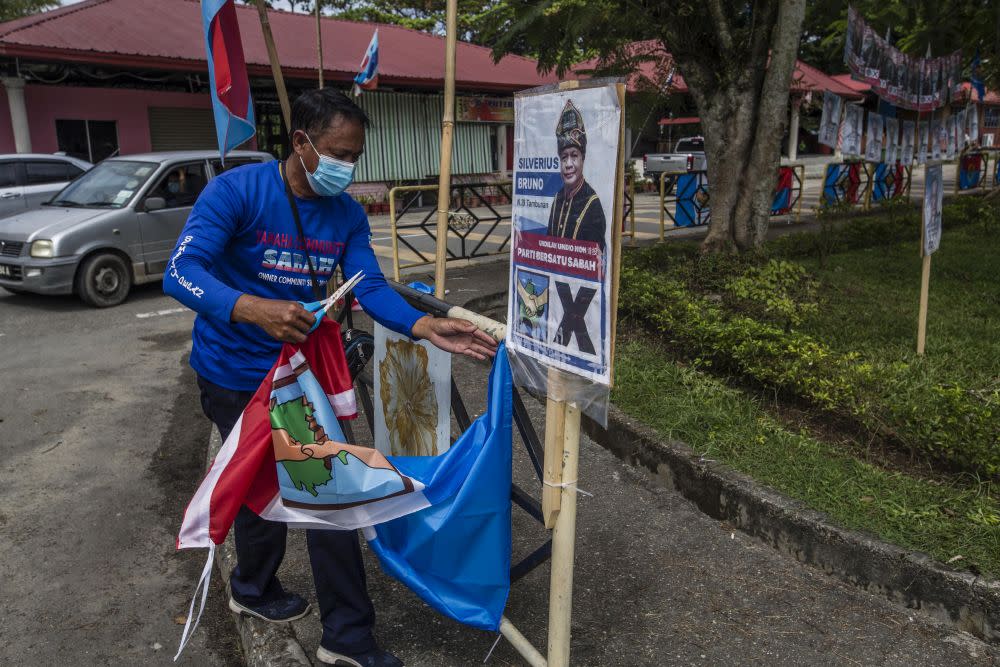 A worker is seen removing posters of PBS candidate Silverius Bruno after the party withdrew from the race to support STAR candidate Datuk Jeffrey Kitingan in Tambunan September 24, 2020. — Picture by Firdaus Latif