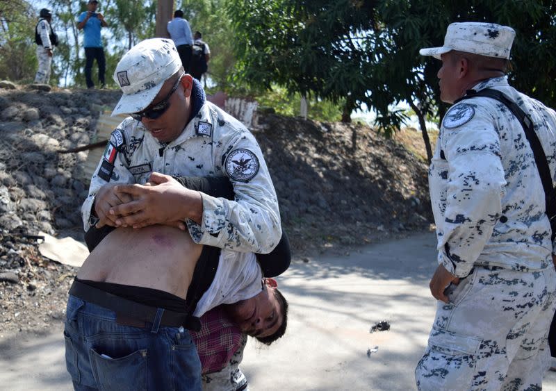 A member of Mexico's National Guard detains a migrant, part of a caravan travelling to the U.S., near the border between Guatemala and Mexico, in Ciudad Hidalgo