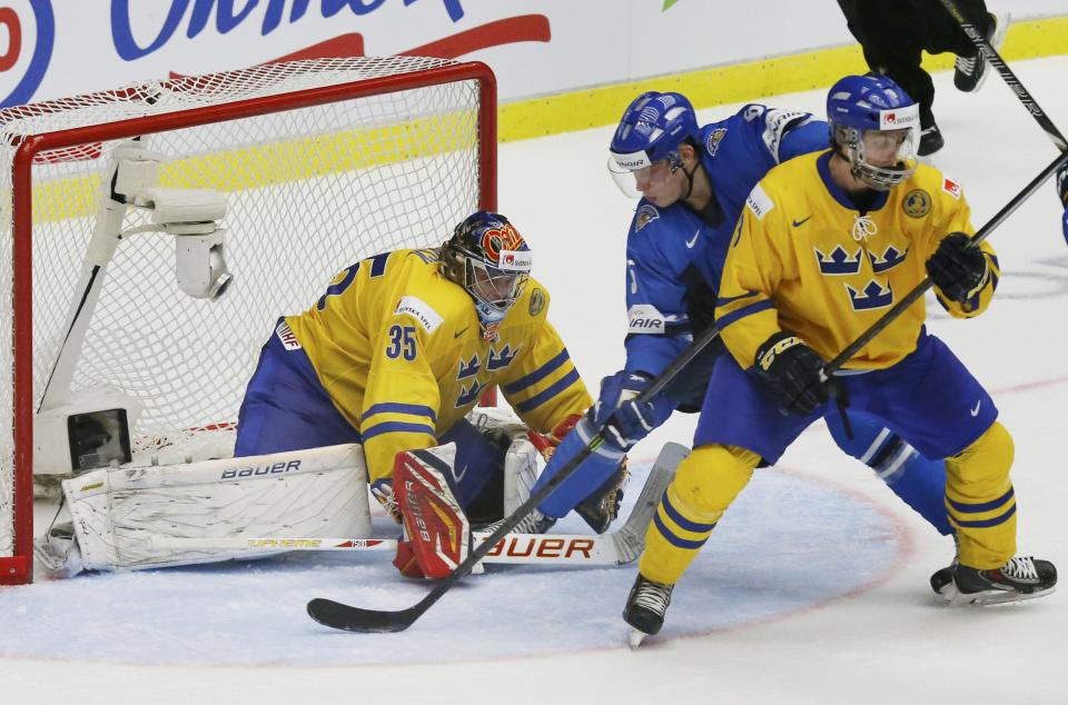 Finland's Rasmus Ristolainen (C) scores the game winning goal on Sweden's goalie Oscar Dansk (L) and Robin Norell during overtime of their IIHF World Junior Championship gold medal ice hockey game in Malmo, Sweden, January 5, 2014. REUTERS/Alexander Demianchuk (SWEDEN - Tags: SPORT ICE HOCKEY)