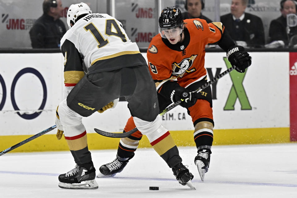 Anaheim Ducks right wing Troy Terry, right, passes the puck between the skates of Vegas Golden Knights defenseman Nicolas Hague during the first period of an NHL hockey game in Anaheim, Calif., Wednesday, Dec. 28, 2022. (AP Photo/Alex Gallardo)
