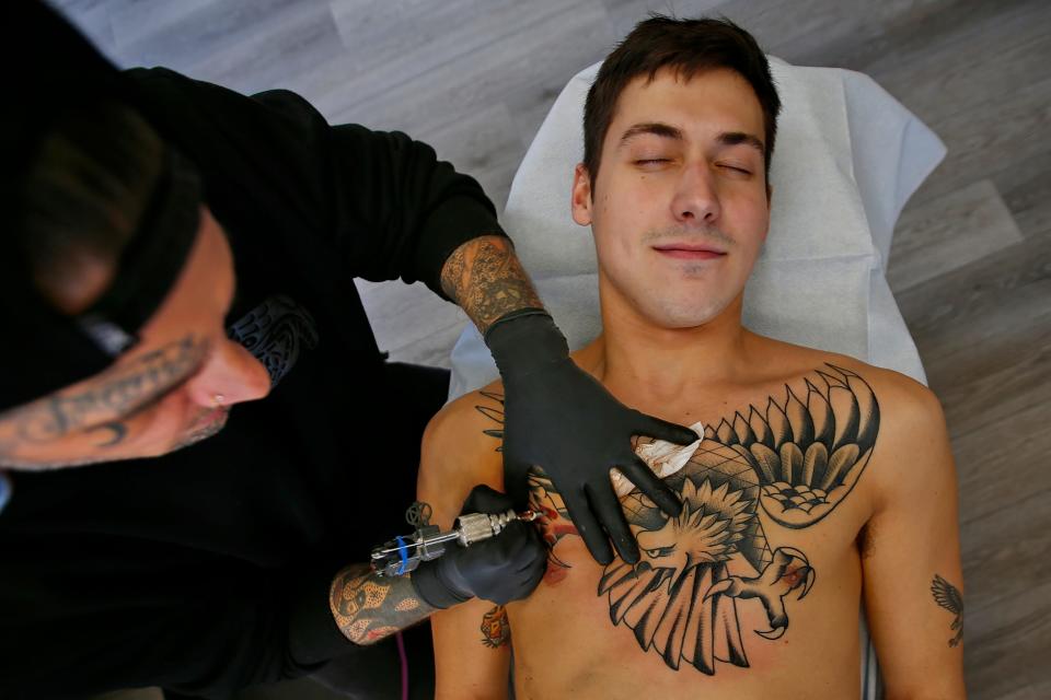 Steve Walters, tattoos one of his eagle designs on the chest of Noah Taylor at New Bedford Tattoo Co in New Bedford.