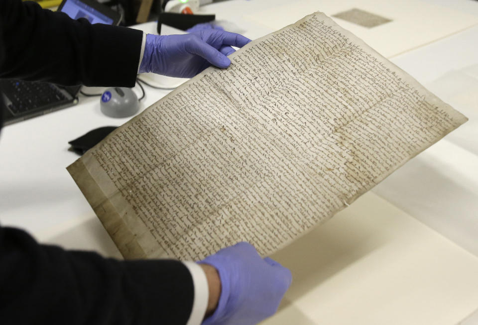 In this Wednesday, Feb. 5, 2014 photo, Chris Woods, director of London's National Conservation Service, very carefully handles the Magna Carta, in Houston. The centuries old parchment will be on display at the Houston Museum of Natural Science for six months starting Feb. 14, 2014. (AP Photo/Pat Sullivan)