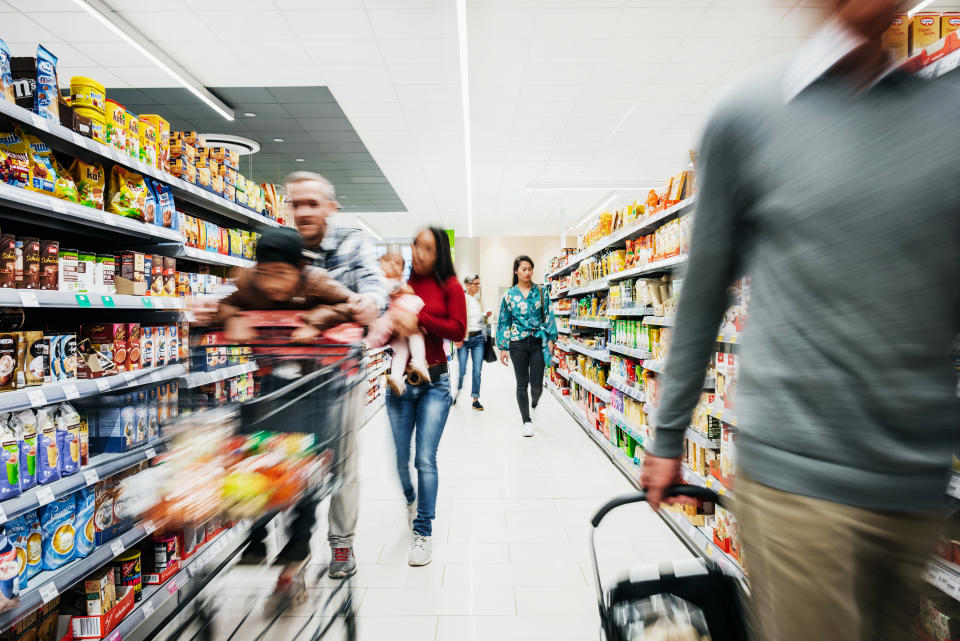 A busy supermarket aisle with various customers buying groceries.