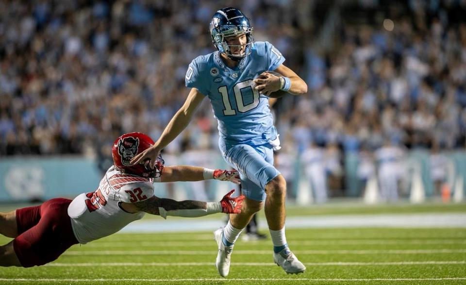 North Carolina quarterback Drake Maye (10) breaks away from N.C. State’s Drake Thomas (32) to score a touchdown on a 14-yard run in the fourth quarter to tie N.C. State 17-17 on Friday, November 25, 2022 at Kenan Stadium in Chapel Hill, N.C.