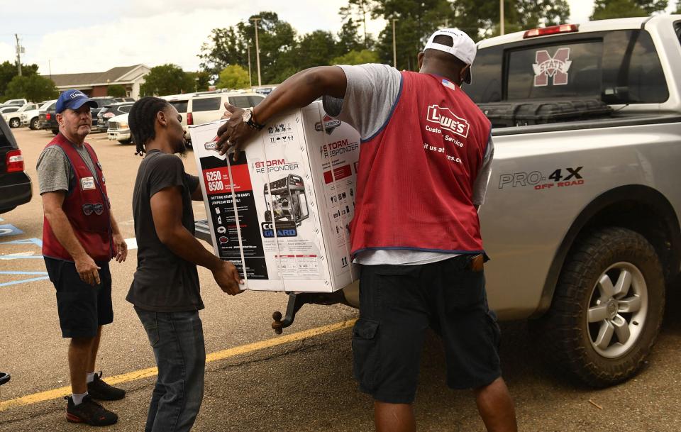 Employees of a Lowe's Home Improvement store help a customer load a Briggs & Stratton generator onto a pick up truck in McComb, Mississippi, as resident prepare for Hurricane Ida on August 28, 2021.