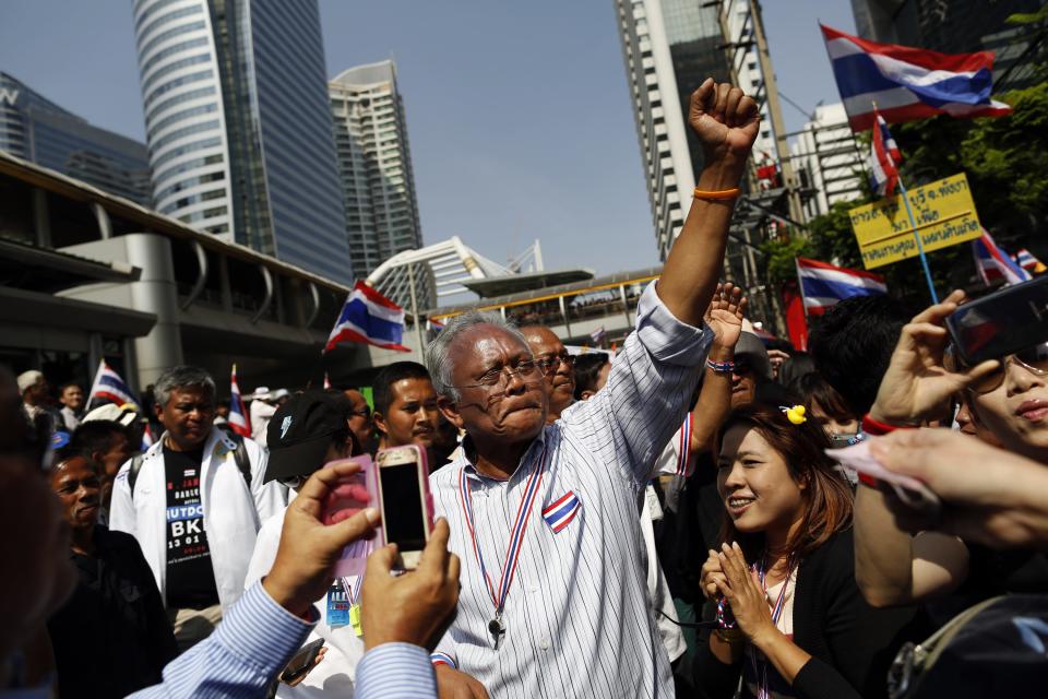 Protest leader Suthep Thaugsuban greets the crowd as he leads anti-government protesters marching through Bangkok's financial district