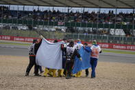 Alfa Romeo driver Guanyu Zhou of China, centre, receives medical treatment after he was involved in a crash at the start of the British Formula One Grand Prix at the Silverstone circuit, in Silverstone, England, Sunday, July 3, 2022. (AP Photo/Frank Augstein)