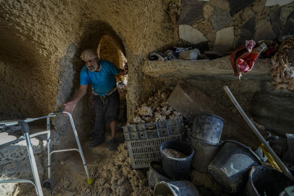 Nissim Kahlon reaches to his walking device in his home chiseled out of the sandstone cliffs overlooking the Mediterranean sea in Herzliya, Israel, Wednesday, June 28, 2023. Over half a century, Kahlon has transformed a tiny cave on a Mediterranean beach into an elaborate underground labyrinth filled with chiseled tunnels, detailed mosaic floors and a network of staircases and mysterious chambers. Fifty years after Kahlon moved into the home, Israel's Environmental Protection Agency has served him an eviction notice, claiming the structure threatens Israel's coastline. (AP Photo/Ariel Schalit)