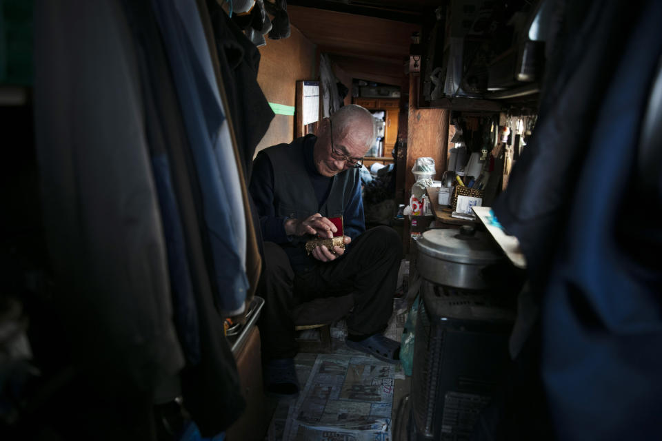 In this Tuesday, Jan. 14, 2020, photo, Mikio Hirau, a 72-year-old homeless man, sits in his shack that he built by himself, in Kawasaki, west of Tokyo. Nearly 16% of Japanese fall below the poverty rate, with annual income below the cutoff of 1.2 million yen ($11,000), according to 2017 Japanese government data. The poverty rate for single-adult households with children is way higher, at 51%. (AP Photo/Jae C. Hong)