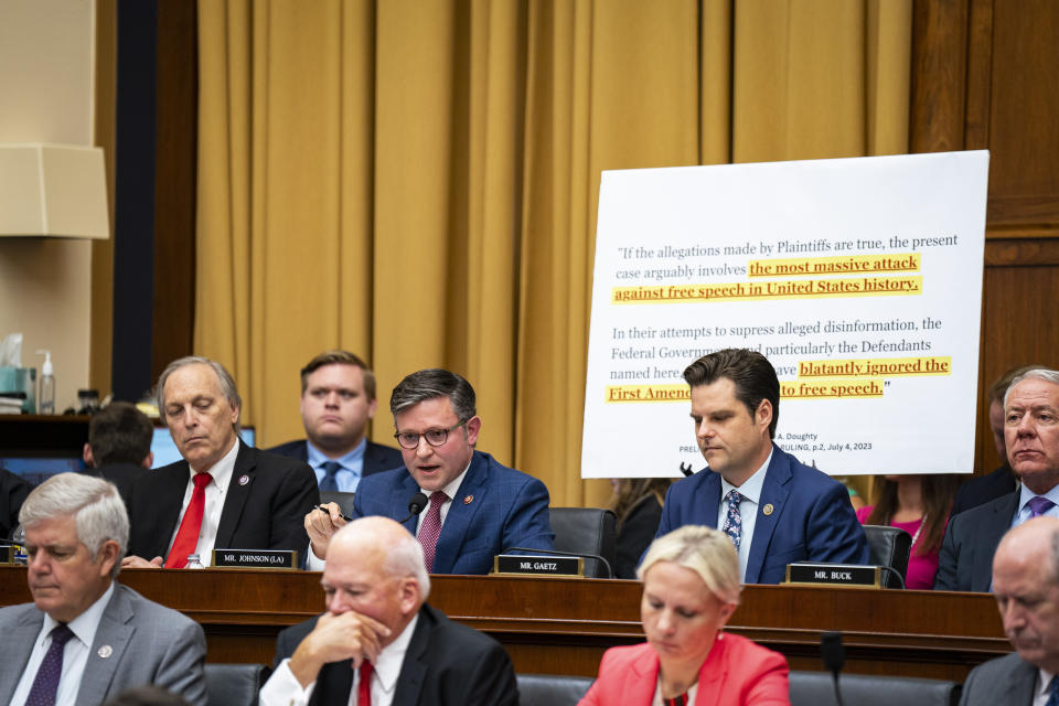 Rep. Mike Johnson and other members of the Committee under a poster that highlights the words: the most massive attack against free speech in United States history.