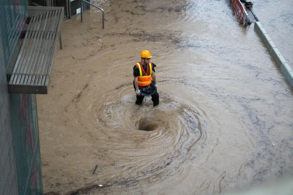A worker works by a whirlpool as flood waters is drained on a road in Hong Kong on September 8, 2023