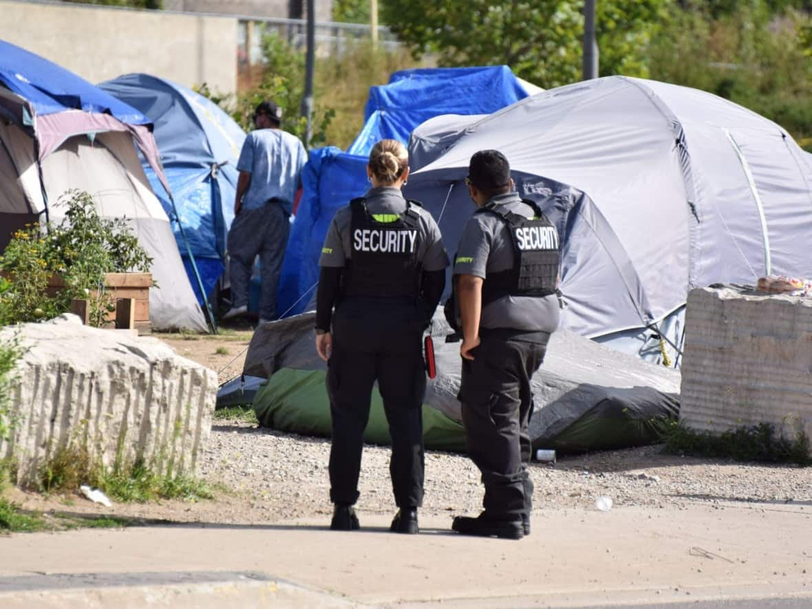 Security patrol an encampment site in Kitchener, Ont., earlier this week. City council has agreed to support the tents while coming up with a long-term plan. (Kate Bueckert/CBC - image credit)