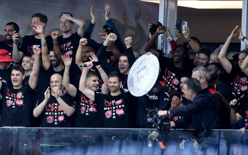 Leverkusen players around coach Xabi Alonso cheer with a stylized championship trophy from the stands into the stadium to the fans who stormed the pitch following the German Bundesliga soccer match between Bayer 04 Leverkusen and SV Werder Bremen at BayArena. Rolf Vennenbernd/dpa