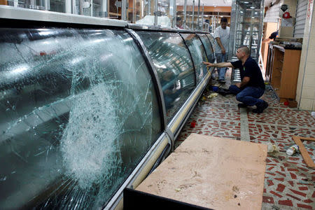 Workers look at the damages in a bakery after it was looted in San Cristobal, Venezuela May 17, 2017. REUTERS/Carlos Eduardo Ramirez