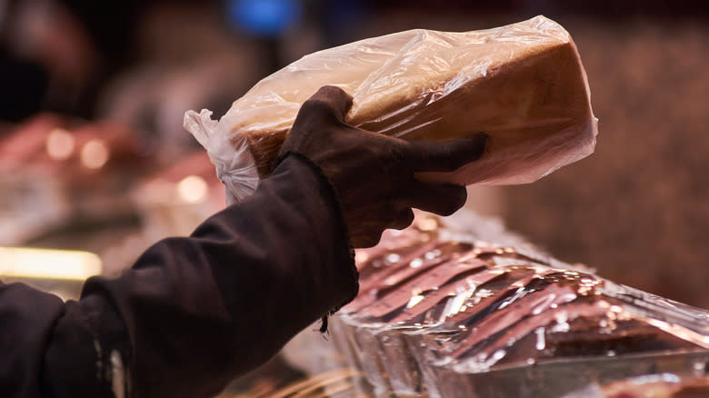 Hand gripping loaf of sliced bread