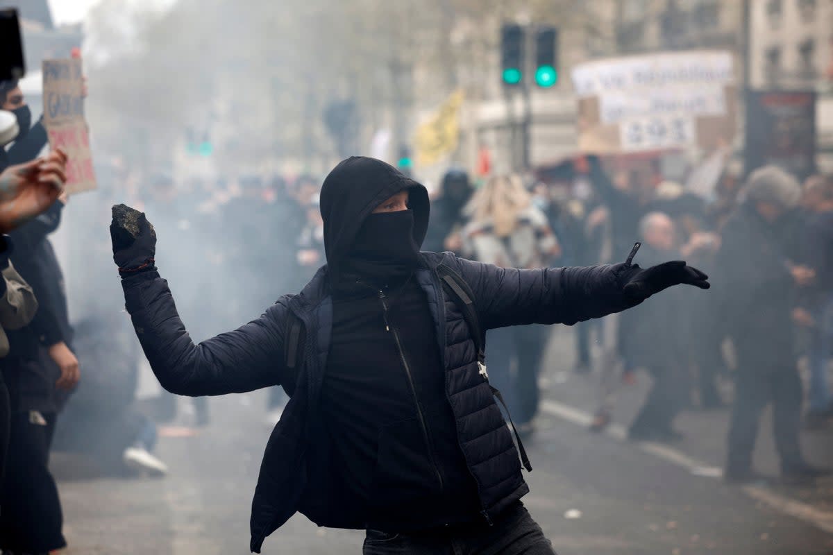 A protester throws a stone at riot police in Paris (REUTERS)