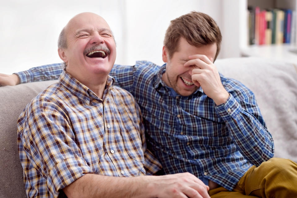 Two men laugh on a couch