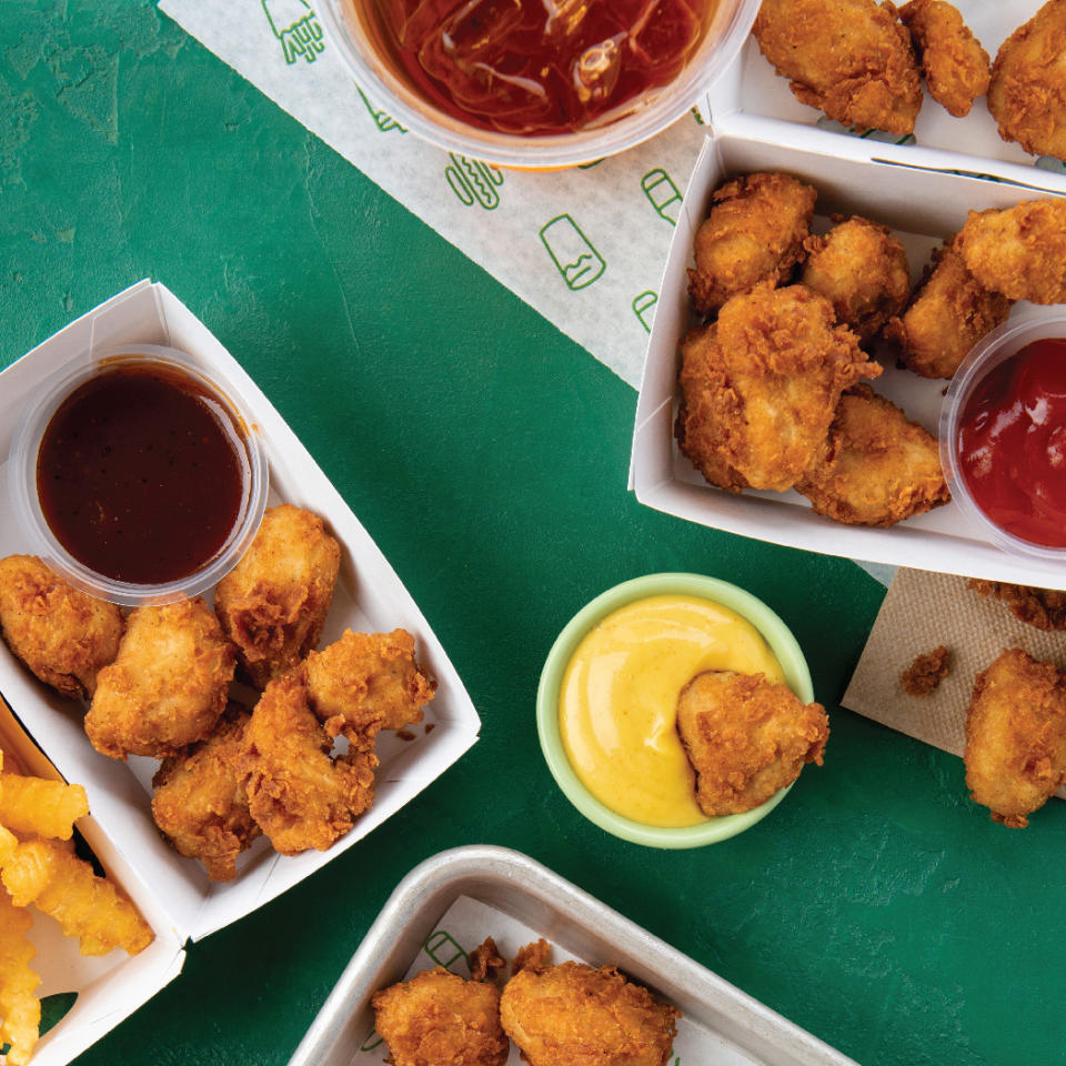 Several boxes of Chick'n Bites with cups of BBQ sauce and honey mustard.