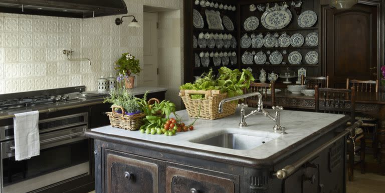 <p>Off-white 19th-century Portuguese tiles add character to a London kitchen. The island is made from a 19th-century cast-iron stove and topped with Carrara marble, and the pendant light is early-20th-century French.<br></p>