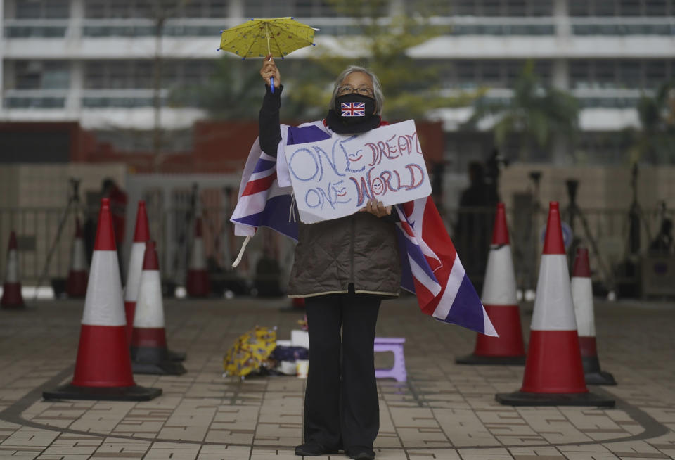 A supporter holds a placard and a small yellow umbrella outside a court in Hong Kong Thursday, March 4, 2021. A marathon court hearing for 47 pro-democracy activists in Hong Kong charged with conspiracy to commit subversion enters its fourth day on Thursday, as the court deliberates over whether the defendants will be granted bail. (AP Photo/Vincent Yu)