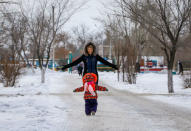 A woman plays with her child in a street in the center of the town of Aksu, north-eastern Kazakhstan, February 21, 2018. REUTERS/Shamil Zhumatov/Files