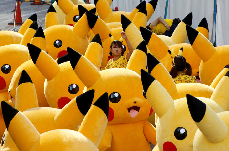 A staff guides performers wearing Pikachu costume