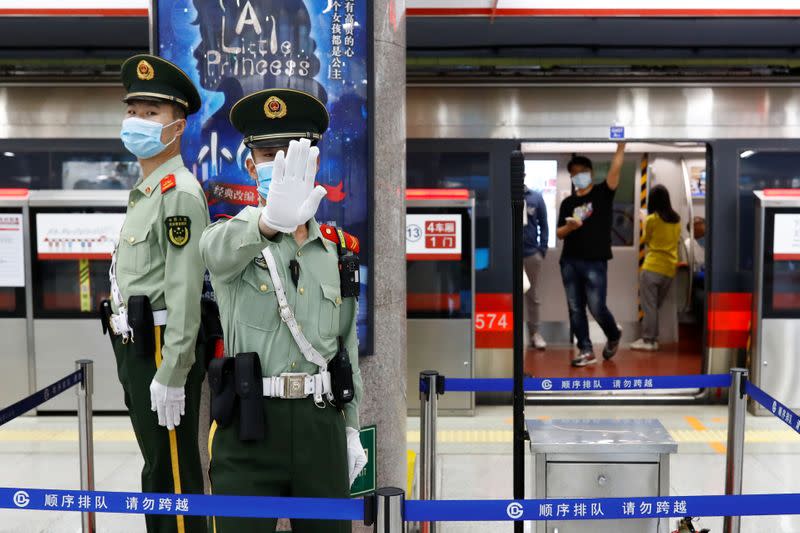 A Paramilitary police officers gestures at the photographer while keeping watch at a station of Line 1 of the metro that runs past the Great Hall of the People