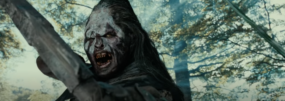 An Uruk-hai aims a bow and arrow at the camera