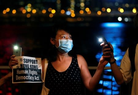 A woman holds a placard as protesters hold hands to form a human chain during a rally to call for political reforms at Tsim Sha Tsui and Hung Hom Promenade in Hong Kong