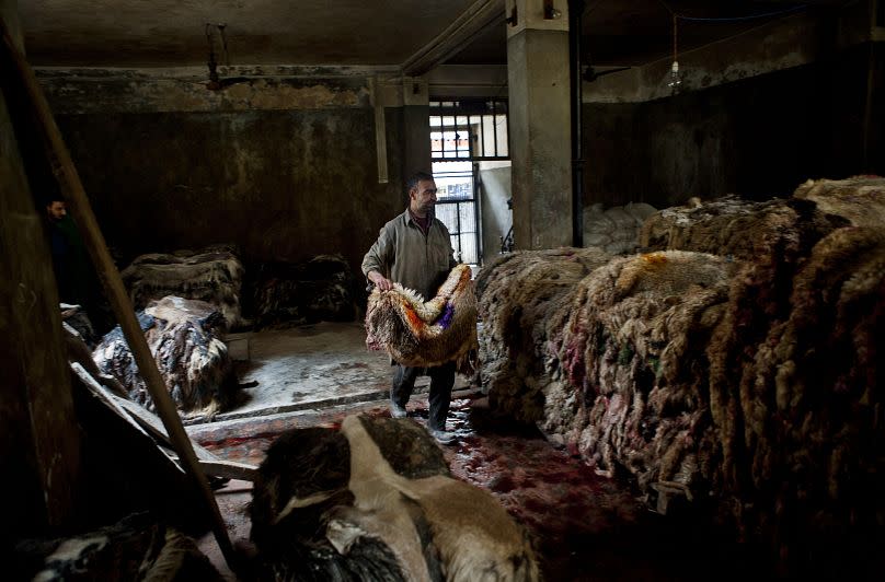 Un trabajador en una fábrica en Srinagar, India, lleva piezas de cuero curtido