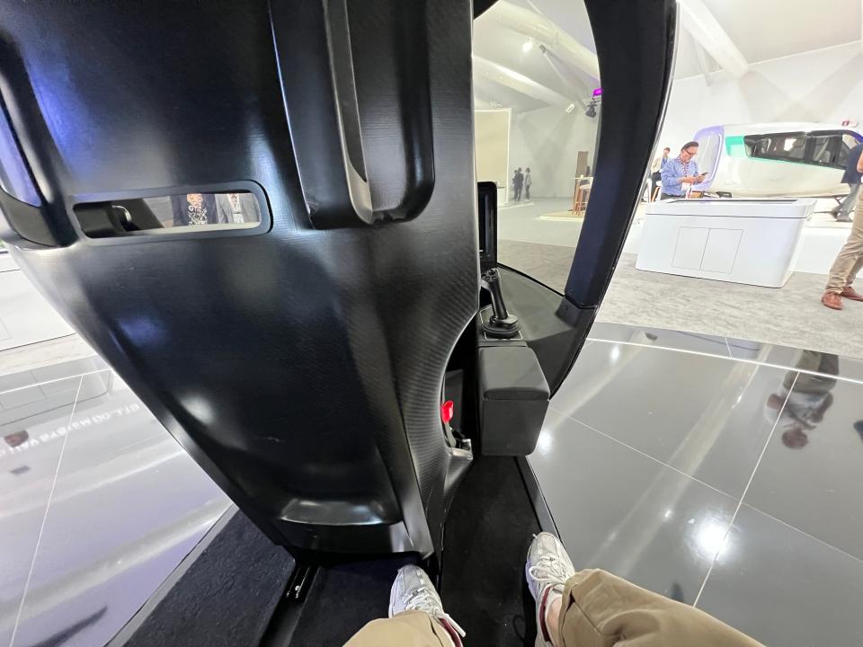 A passenger's point of view onboard the static display of an Archer Midnight eVTOL shows a narrow platform with the doors open