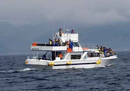 Tourists on a whale watching tour boat sails in the sea near Rausu