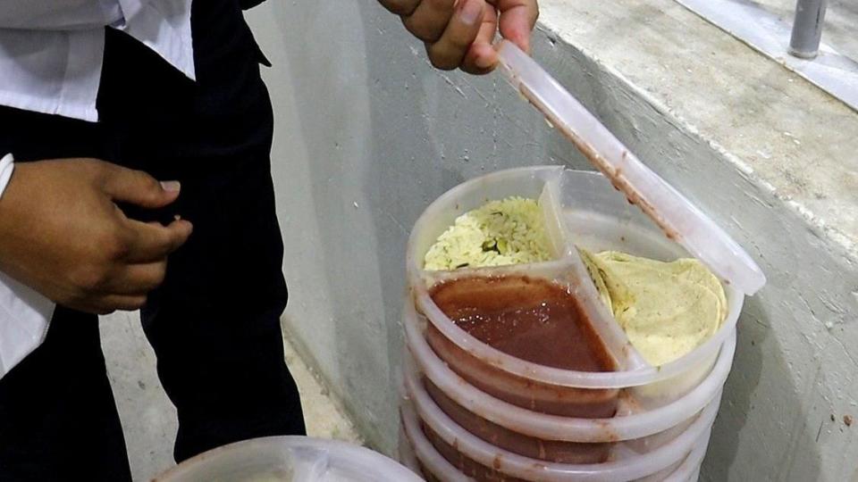 Un táper con arroz, frijoles y tortillas de maíz