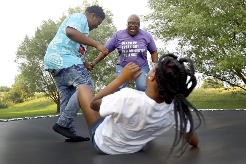 Delicia Harris, center, laughs as her youngest daughter, Antoinette Harris falls back on a trampoline as Antoinette's friend Shardon Layne joins in, Thursday, July 22, 2021 at their home in Loves Park, Ill. The eruption in violence in the city among people stuck at home wasn't a surprise to Harris who has worked with youth programs in Rockford. The money flowing to cities and states from the American Rescue Plan is so substantial and can be used for so many purposes that communities across the U.S. are trying out new, longer-term ways to fix what’s broken in their cities. (AP Photo/Shafkat Anowar)