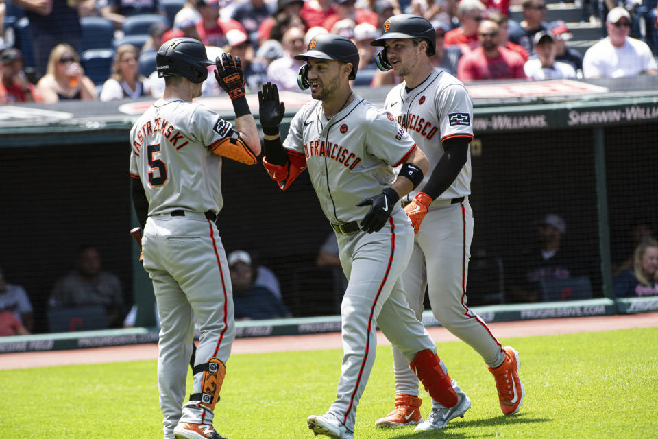 San Francisco Giants' Mike Yastrzemski (5) congratulates Michael Conforto, center, who hit a two-run home run off Cleveland Guardians starting pitcher Carlos Carrasco and Patrick Bailey, right, follows during the second inning of a baseball game in Cleveland, Sunday, July 7, 2024. (AP Photo/Phil Long)