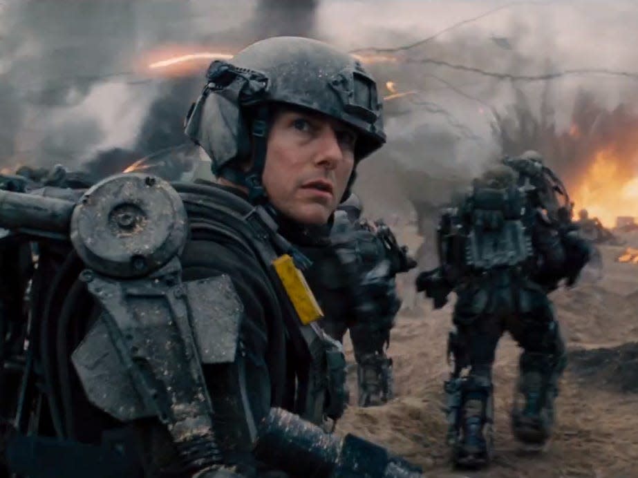 Tom Cruise in "Edge of Tomorrow" in military gear and explosion behind him