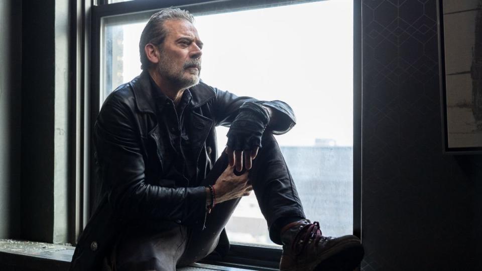 Negan sits in a window sill wearing a black leather jacket in dead city 