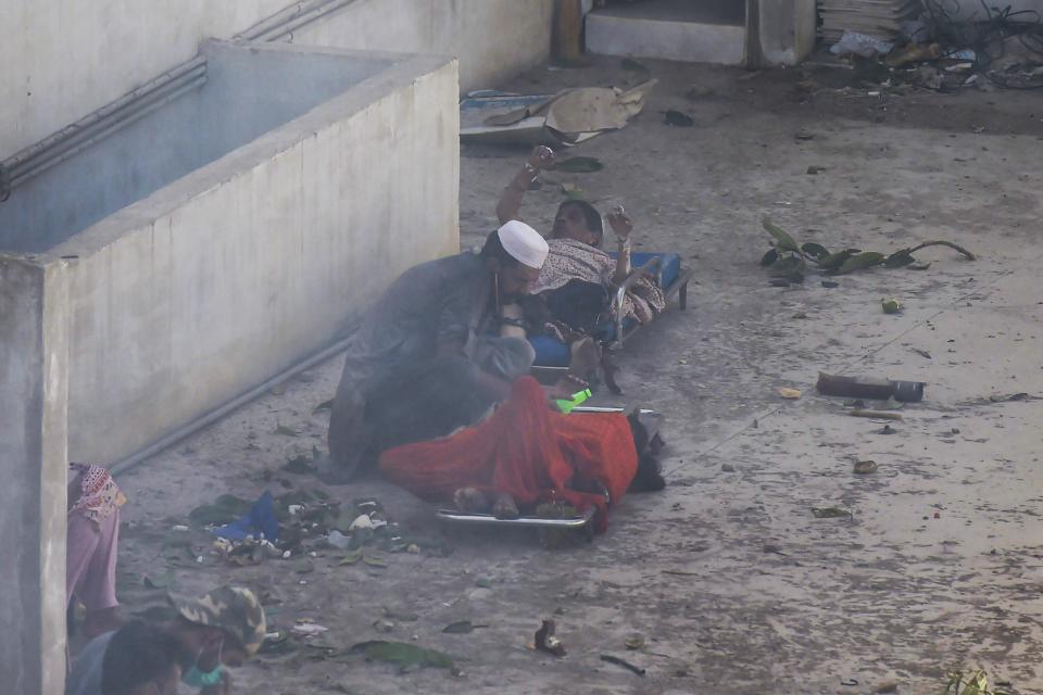 A man helps injured victims after a Pakistan International Airlines flight crashed in a residential neighbourhood in Karachi on May 22, 2020. - A Pakistan passenger plane with more than 100 people believed to be on board crashed in the southern city of Karachi on May 22, the country's aviation authority said. (Photo by Asif HASSAN / AFP) (Photo by ASIF HASSAN/AFP via Getty Images)