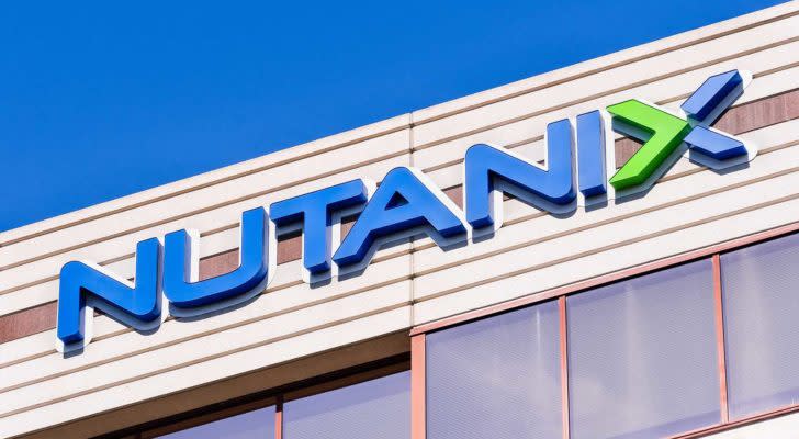 An image of a blue and green "Nutanix" logo on the front of a tan building, a row of windows below the sign, and the blue sky in the background.