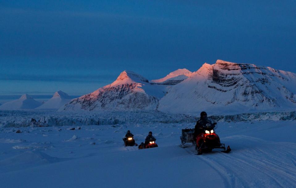 NPI (Norwegian Polar Institute) scientists ride their snowmobiles as the sun sets on Kongsfjord and Kronebreen glaciers (Reuters)