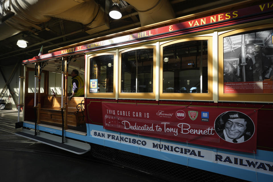 A cable car dedicated to Tony Bennett makes its way out of a barn to begin a run in San Francisco, Thursday, March 14, 2024. Tony Bennett loved San Francisco and its cable cars and in return, the city has dedicated one of those cable cars to the famous crooner who died in July. Cable car 53, built in 1907, has several plaques and painted gold ribbons remembering Bennett. (AP Photo/Eric Risberg)