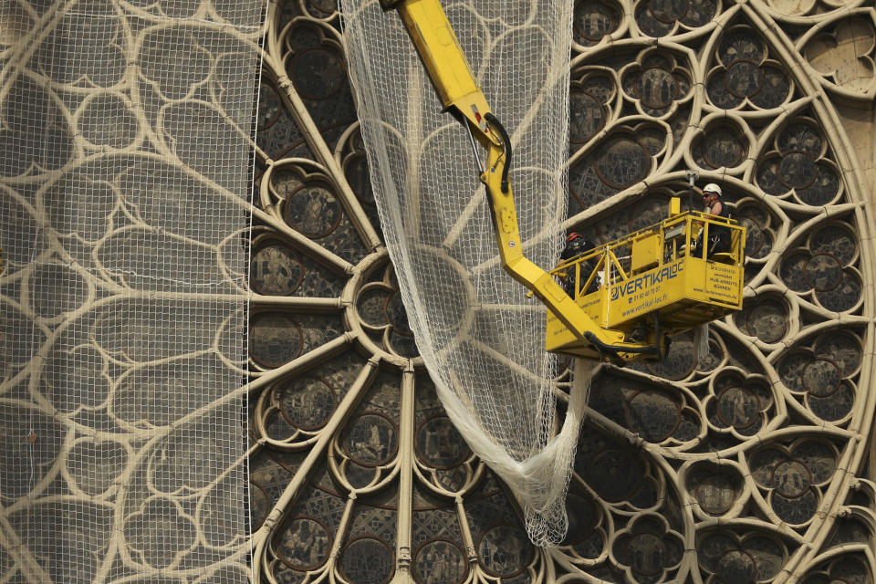 Workers fix a net to cover one of the iconic stained glass windows of the Notre Dame Cathedral in Paris, Sunday, April 21, 2019. The fire that engulfed Notre Dame during Holy Week forced worshippers to find other places to attend Easter services, and the Paris diocese invited them to join Sunday's Mass at the grandiose Saint-Eustache Church on the Right Bank of the Seine River. (AP Photo/Francisco Seco)