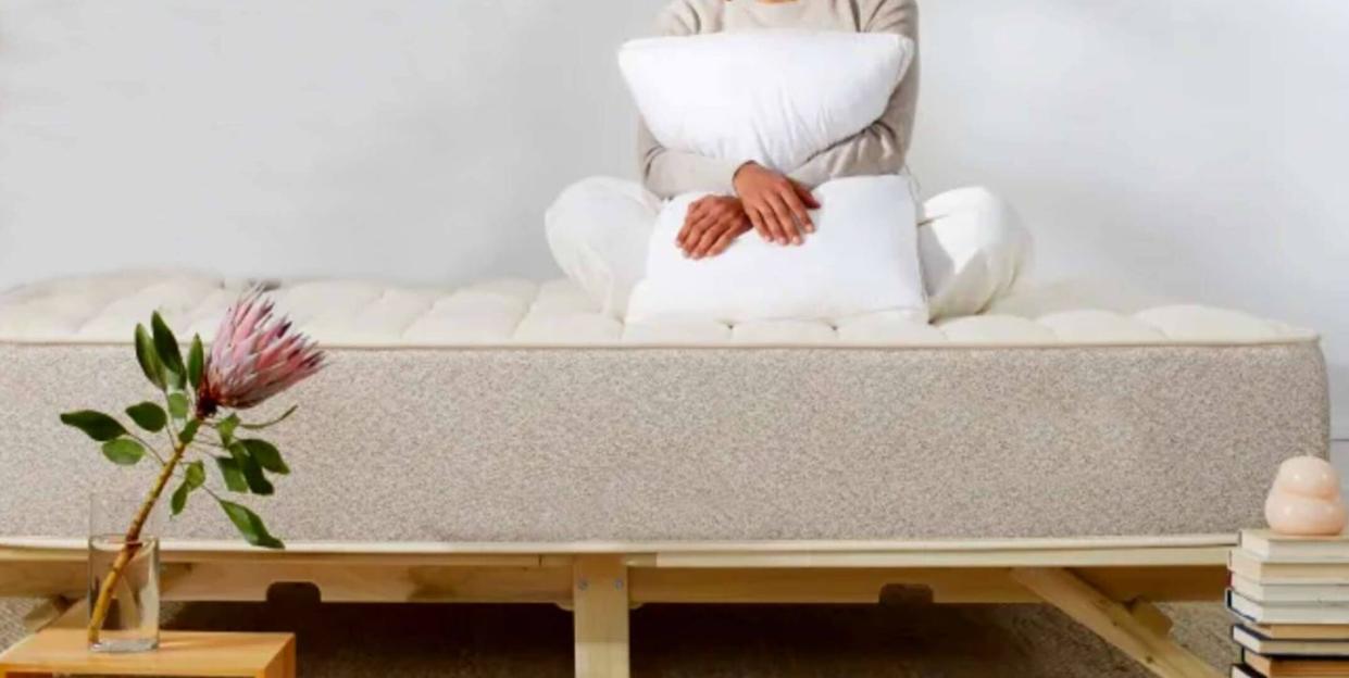 person sitting on a mattress and holding a pillow