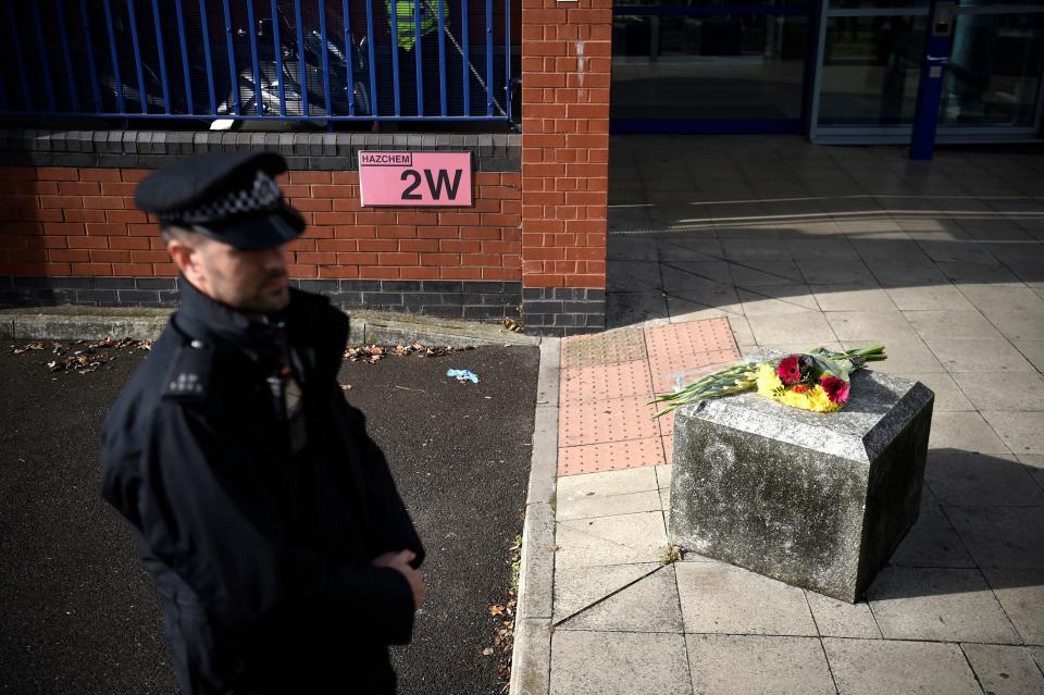 A police officer stands near flowers placed outside the Croydon Custody Centre in south London on September 25, 2020, following the shooting of a British police officer by a 23-year-old man being detained at the centre. - A British police officer was shot dead in the early hours of Friday morning, Scotland Yard said, the first officer to be killed by gunfire while on duty in over eight years. (Photo by DANIEL LEAL-OLIVAS / AFP) (Photo by DANIEL LEAL-OLIVAS/AFP via Getty Images)