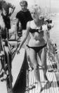 <p>French film star Catherine Deneuve relaxes aboard a sailboat with director Roger Vadim. While enjoying a leisurely day off, the actress soaked up the sun in a black bikini. </p>