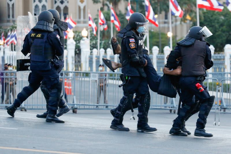 A pro-democracy protester is detained by police officers in front of the Government House during a rally in Bangkok